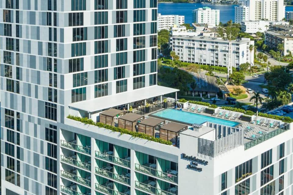 Aerial view of rooftop pool and lounge area in high-rise urban residential building