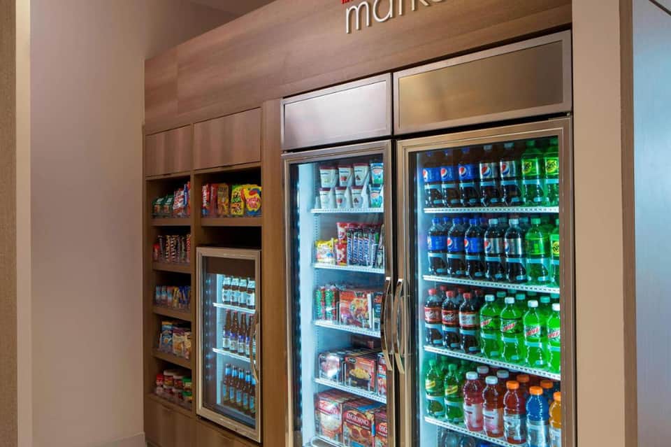 Market kiosk with refrigerated vending machines stocked with beverages and snacks