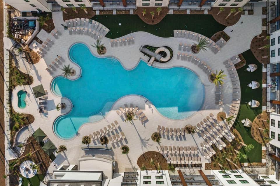 Aerial view of resort's curved pool complex surrounded by lounge chairs and palm trees