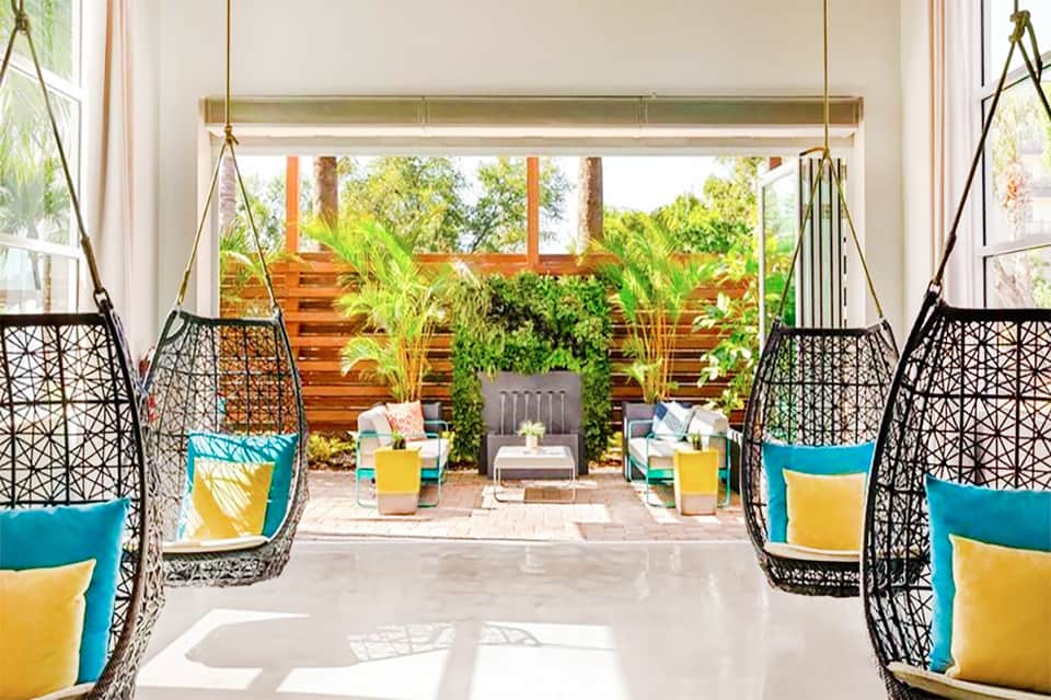 Modern lounge area with black hanging pod chairs and teal cushions overlooking garden