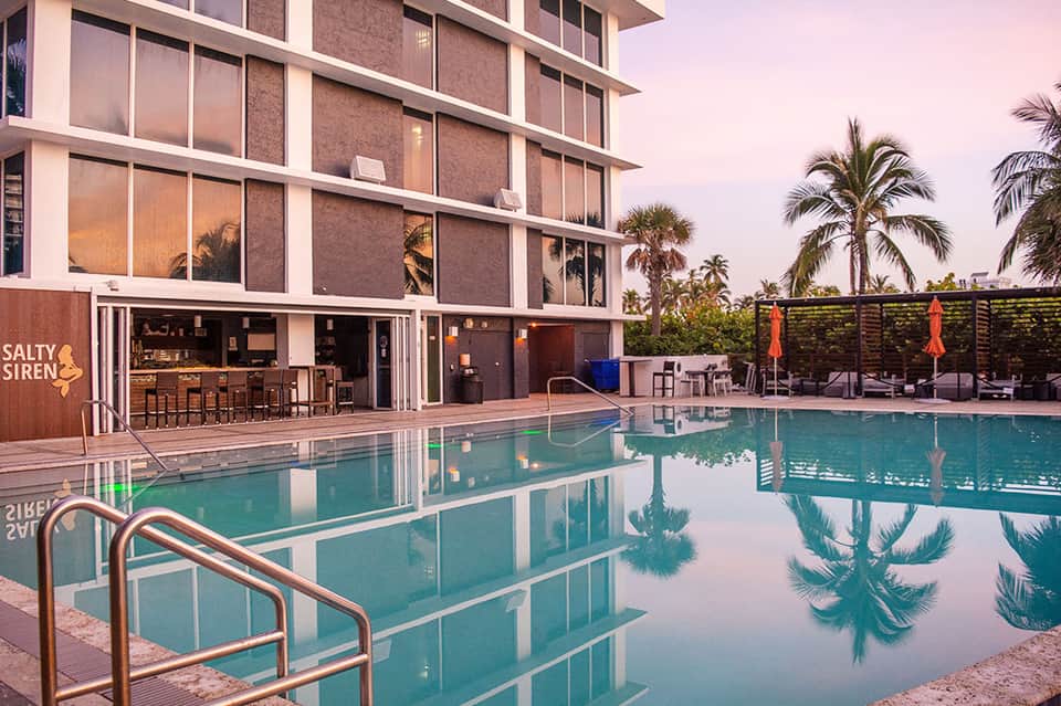 Contemporary resort pool at dusk with modern building and Salty Siren bar