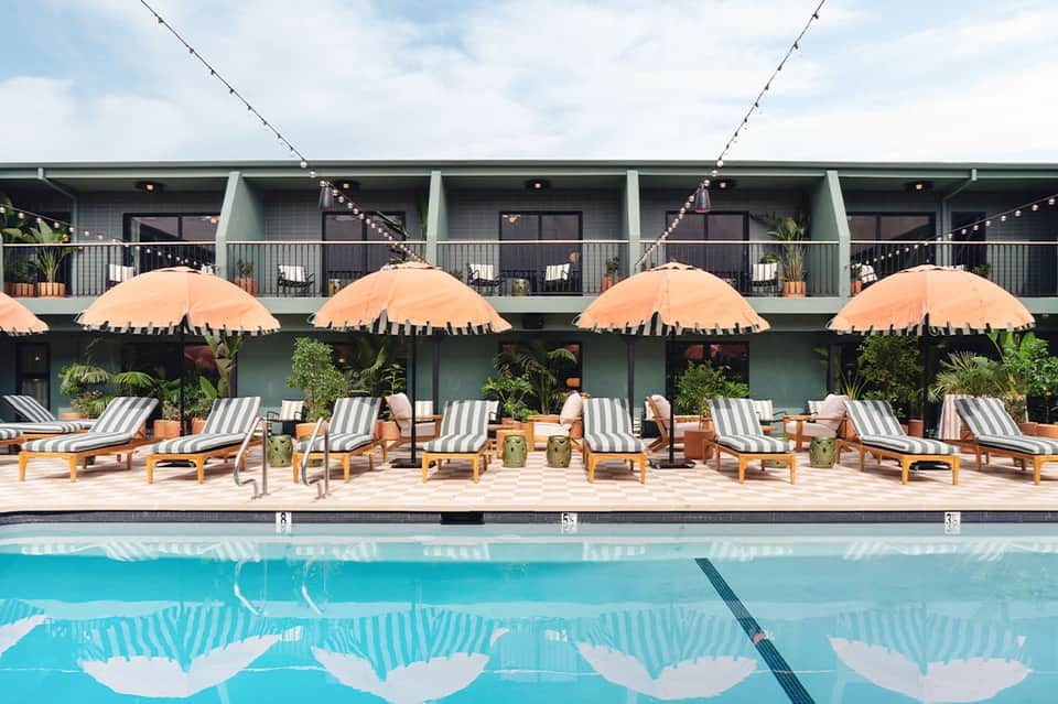 Resort pool with striped loungers, orange umbrellas, and modern building
