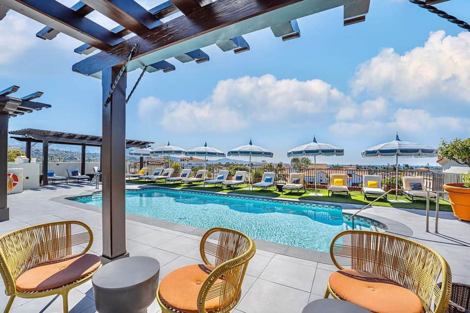 Upscale poolside lounge with pergola, woven chairs, white umbrellas and mountain views
