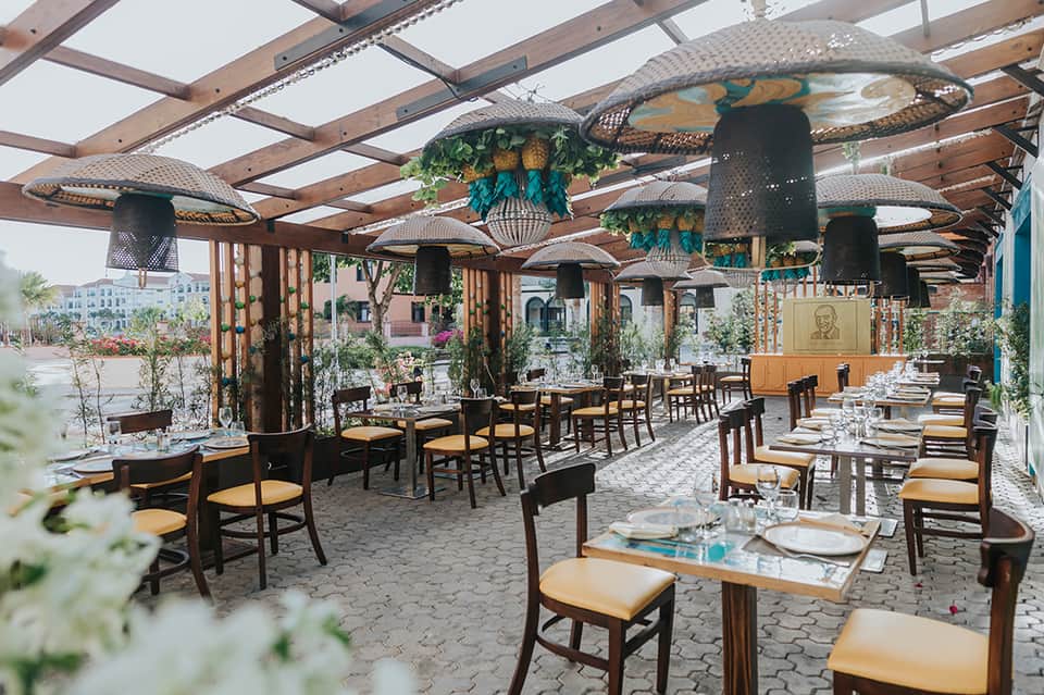 Upscale outdoor restaurant terrace with pergola, hanging plants, and set dining tables