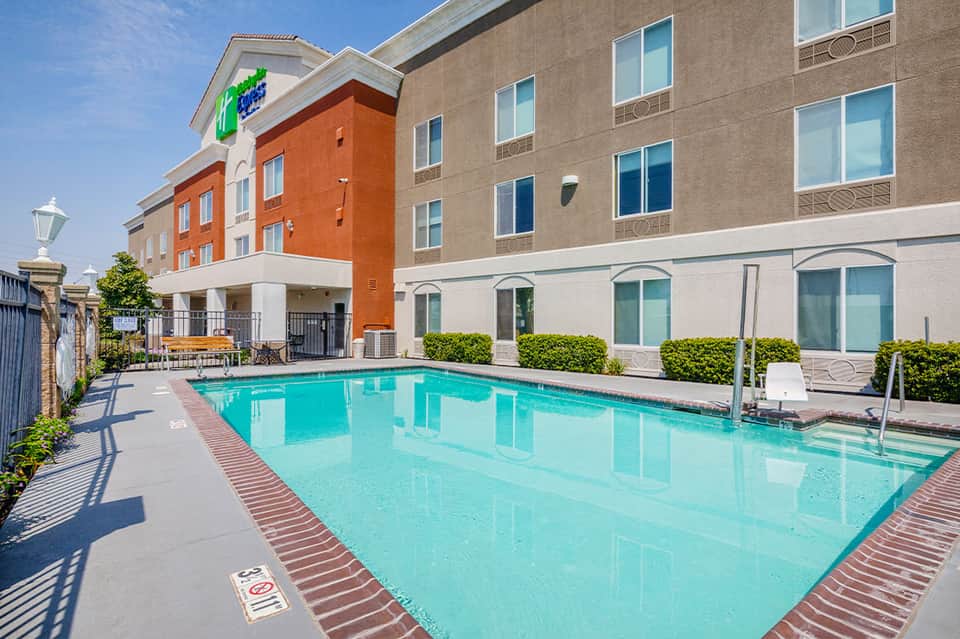 Rectangular outdoor pool with turquoise water flanked by modern hotel building and landscaping