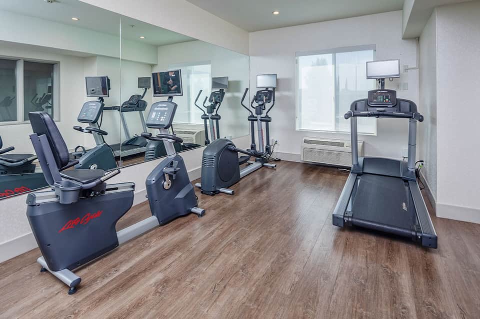 Modern fitness center with cardio equipment, exercise bikes, treadmill, and mirrored walls
