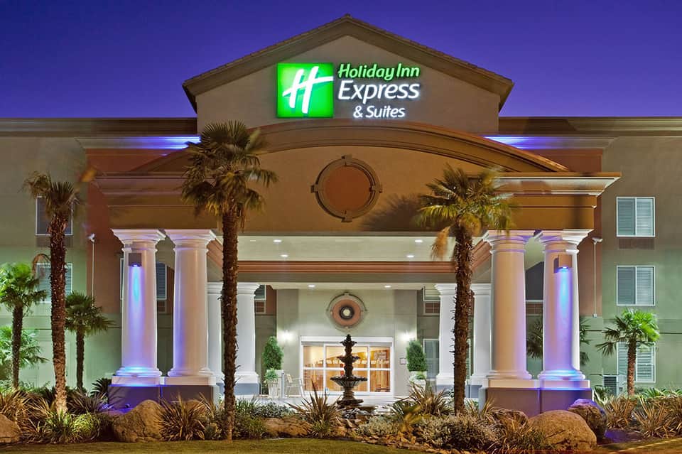 Holiday Inn Express & Suites exterior at dusk with illuminated columns and palm trees