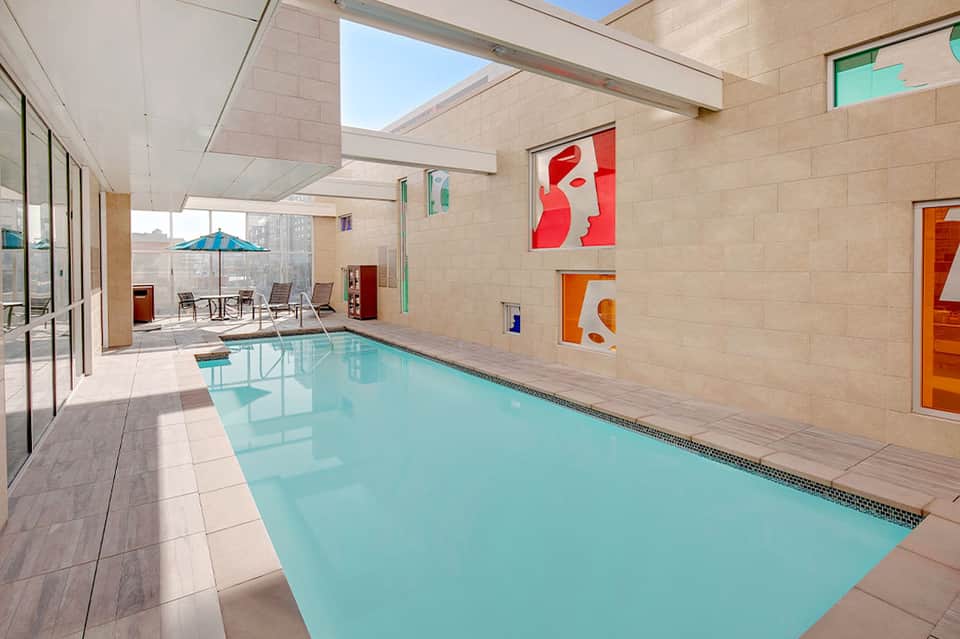 Indoor lap pool in bright atrium space with skylights and colorful wall artwork