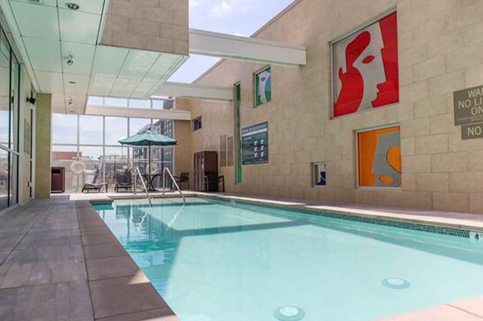 Indoor swimming pool with skylights, colorful artwork, and glass doors to outdoor deck