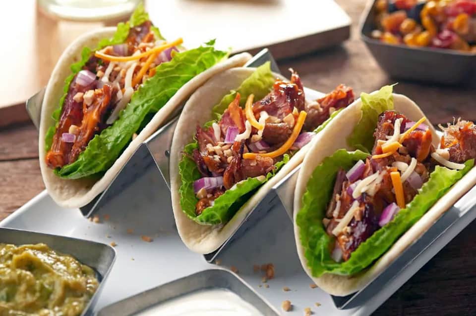 Three gourmet lettuce wraps with meat and vegetables on white plate