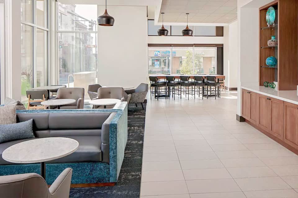 Contemporary resort lobby with teal accents, modern seating, bar area, and pendant lighting