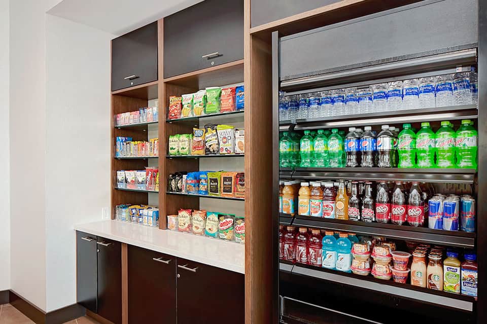 Convenience store snack area with wooden shelving, vending machine, and stocked beverages