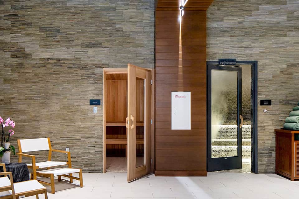 Spa entrance with wooden sauna doors, stone accent wall, and minimalist modern design