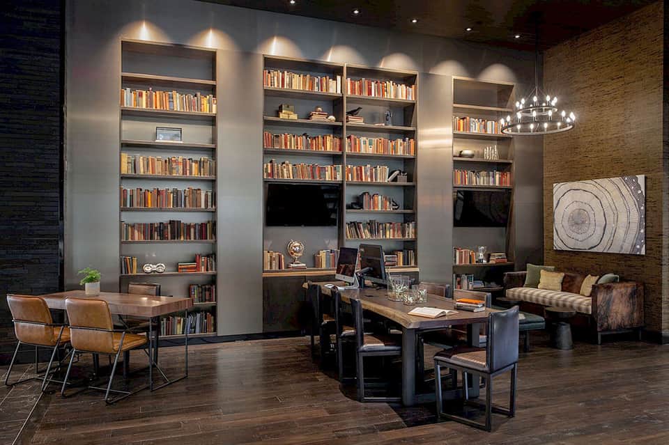 Upscale library lounge with floor-to-ceiling bookshelves, desk areas, and contemporary furnishings