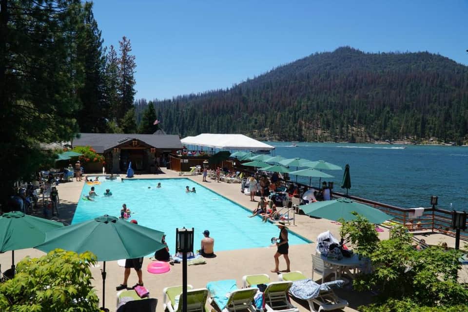 Mountain lake resort pool surrounded by dense forest and pine trees with dock