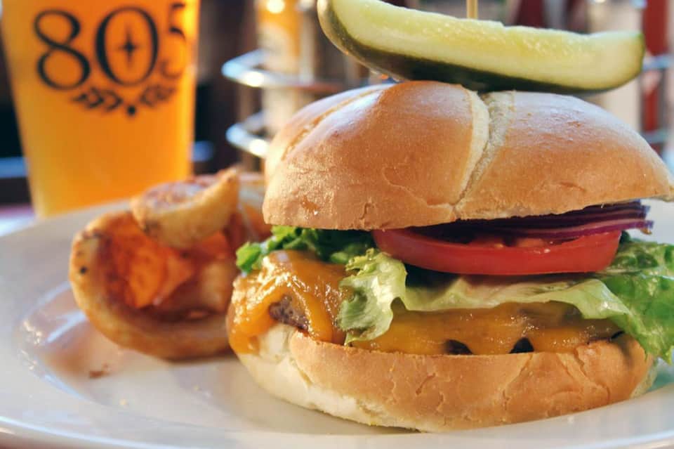 Gourmet burger with cheese and vegetables, served with fries