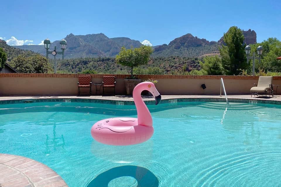 Resort pool with pink flamingo float and mountain backdrop surrounded by desert landscape