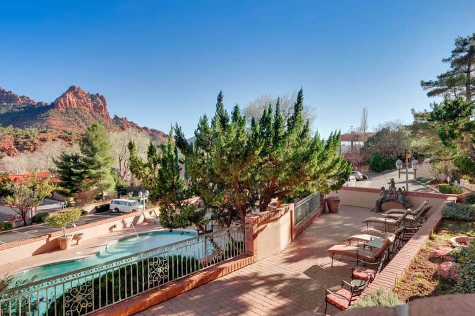 Resort courtyard with turquoise pool, red rock mountain views, and lounge seating