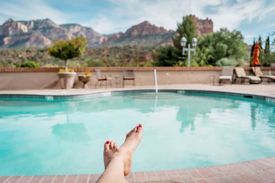 Resort swimming pool with turquoise water and red rock mountain formations in background