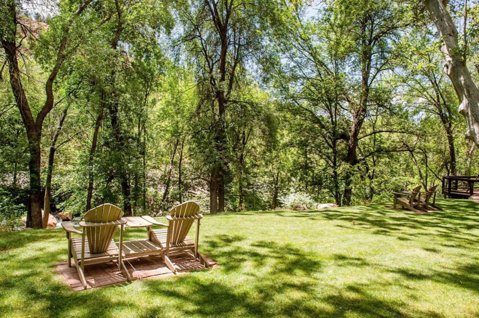 Peaceful resort lawn with Adirondack chairs under leafy trees and natural shade