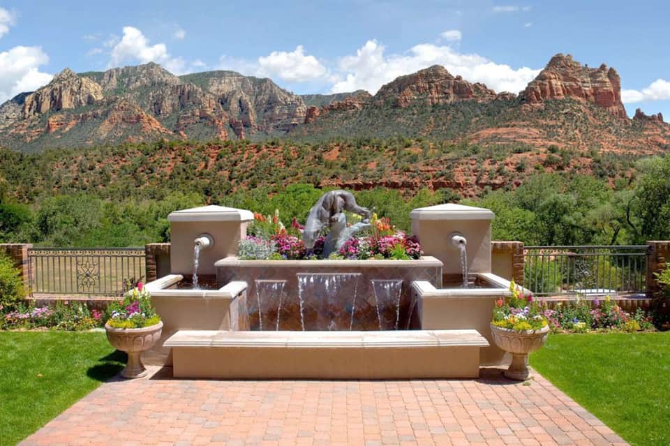 Fountain with statue and flowering plants overlooking red rock mountains and valley