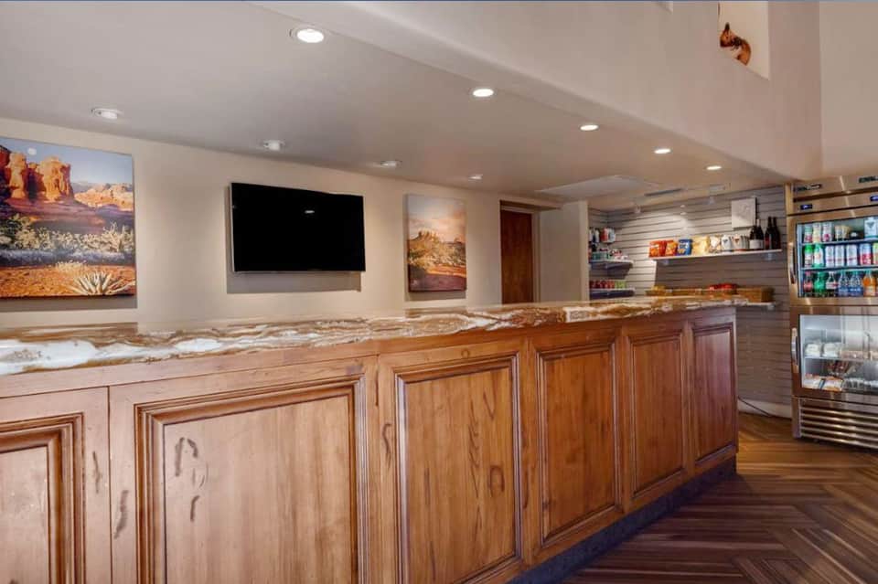 Resort bar and lounge interior with wooden cabinetry, granite countertop, TV, and beverage coolers