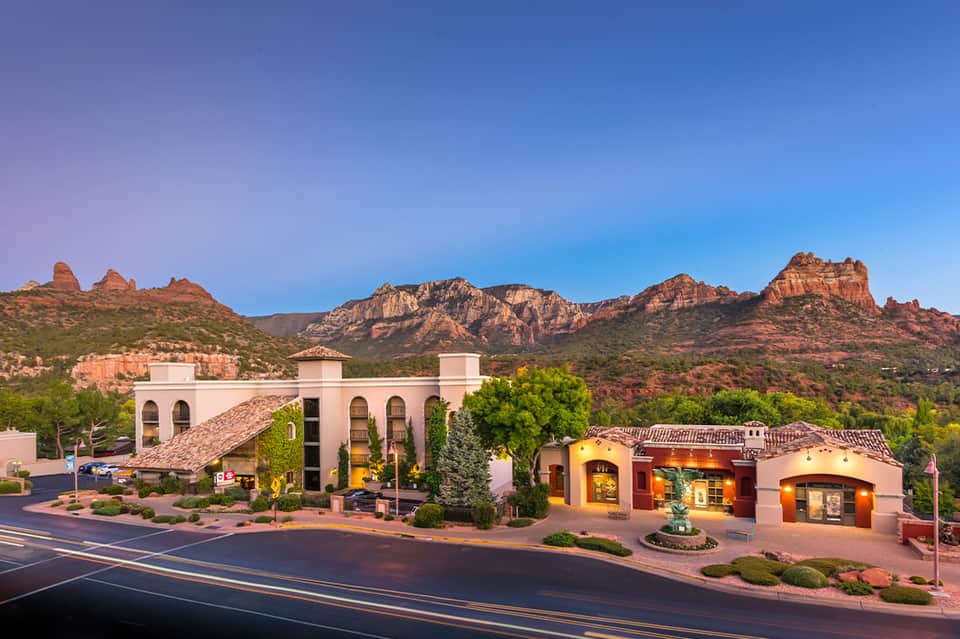 Southwestern-style building with pink stucco against red rock mountains and clear blue sky