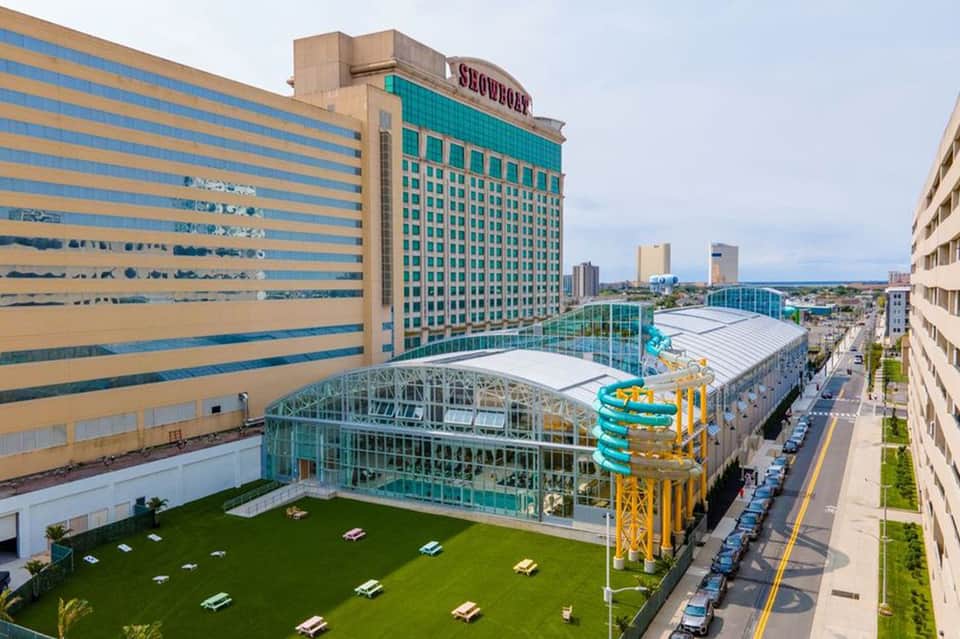 Aerial view of waterpark with turquoise pools, yellow slides, green lawn, and surrounding hotel buildings