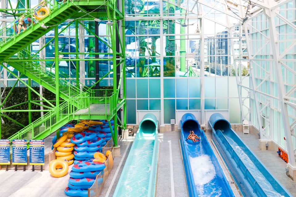 Indoor water park with colorful slides, tube floats, and green metal framework structure