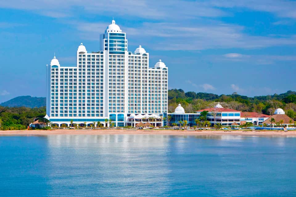 Beachfront resort with distinctive white multi-story architecture and dome rooftops overlooking turquoise water