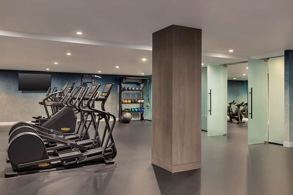 Contemporary fitness center with cardio equipment, weights, and glass-enclosed studio space