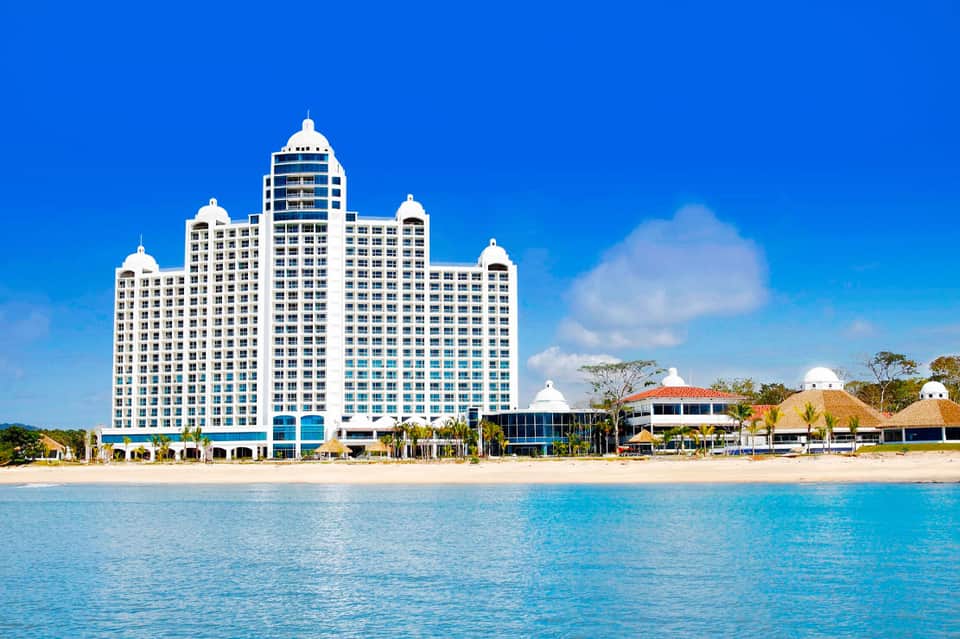 White high-rise beachfront hotel with distinctive architecture viewed from turquoise ocean waters