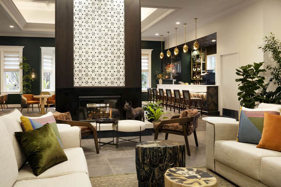 Upscale hotel lobby with fireplace, pendant lights, modern seating, and bar area
