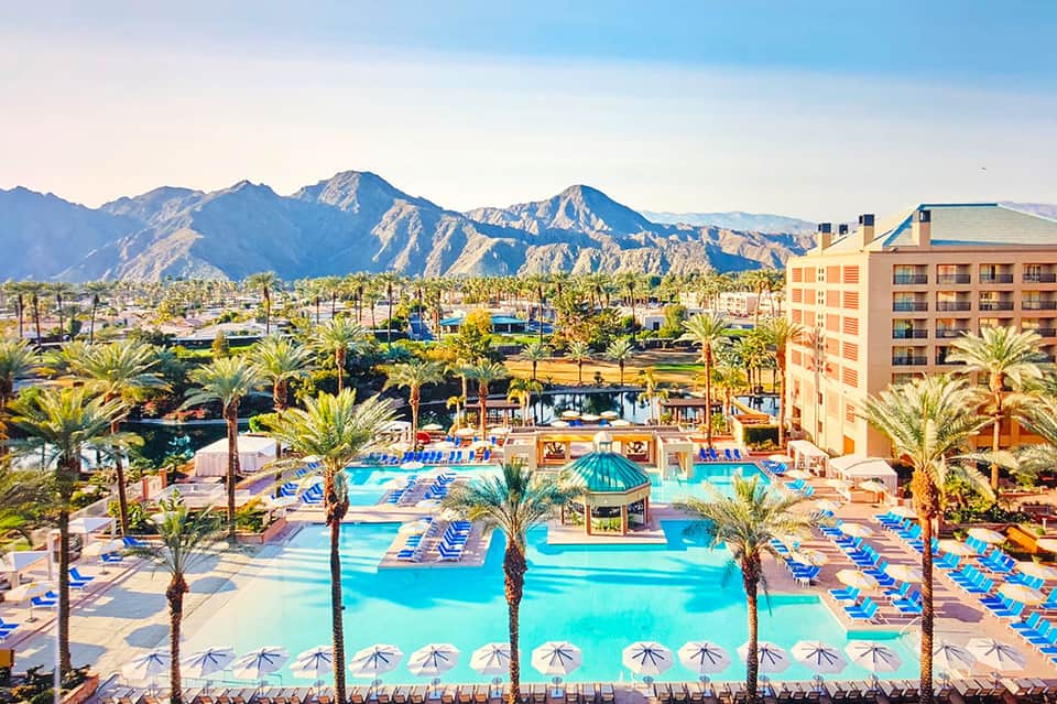 Resort pool complex with multiple pools, palm trees, and mountain backdrop in desert landscape