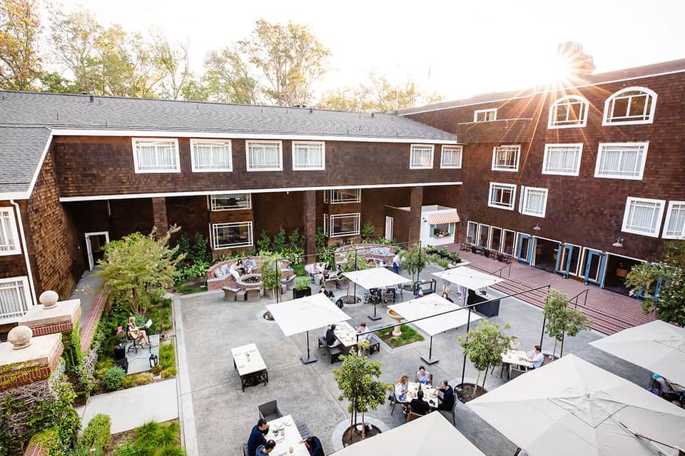 Courtyard gathering space with picnic tables, umbrellas, and brick colonial-style building