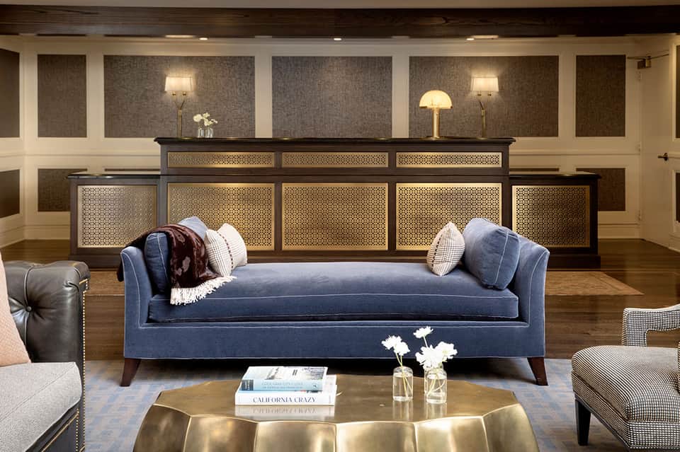 Elegant hotel lobby with blue sofa, decorative lighting, and ornate wooden reception desk