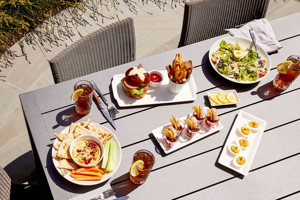 Outdoor dining table with appetizers, salads, and beverages