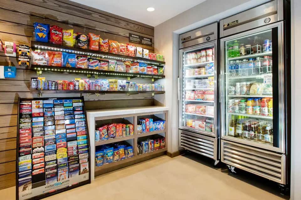 Snack bar with lit shelves of packaged foods and two refrigerated beverage cases
