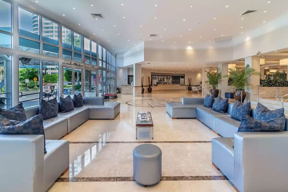 Spacious modern hotel lobby with light marble floors, contemporary seating, and floor-to-ceiling windows