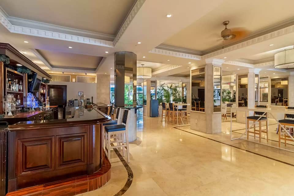 Upscale hotel lobby with curved bar, polished floors, elegant pillars, and refined interior design