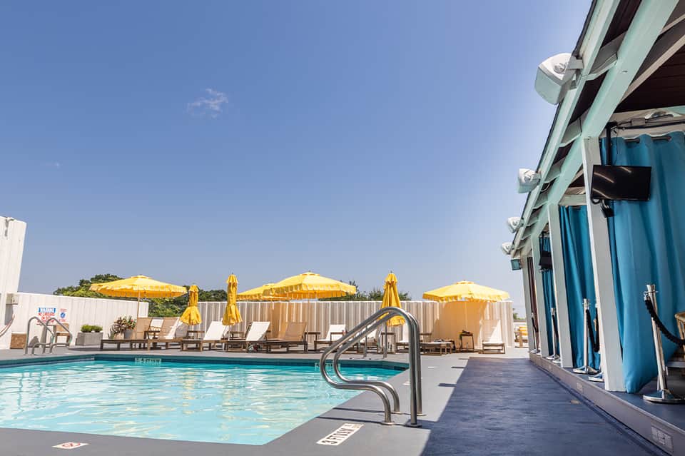 Indoor swimming pool with yellow umbrellas, lounge chairs, and glass-walled facility