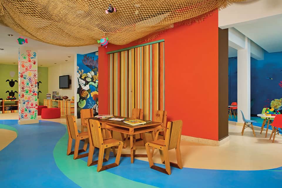 Colorful children's playroom with bright walls, fishing net ceiling, and wooden furniture
