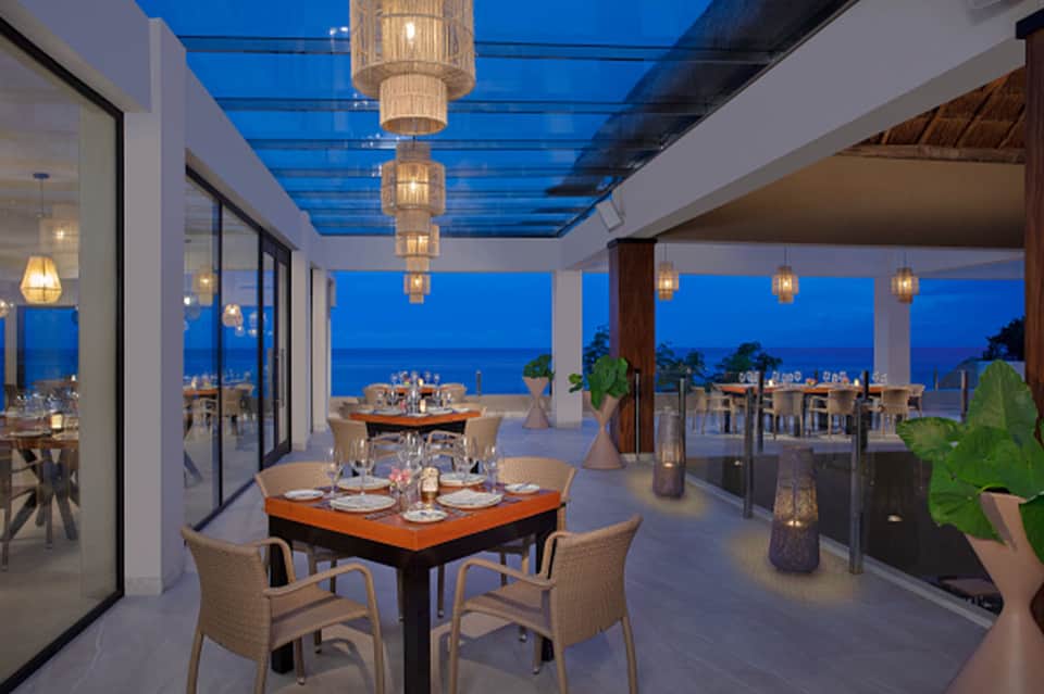Fine dining terrace with ocean sunset view and decorative hanging lanterns