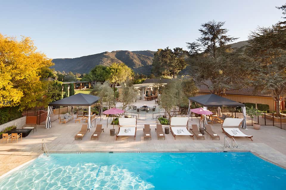 Resort pool with mountain views, sun loungers, umbrellas, and autumn foliage