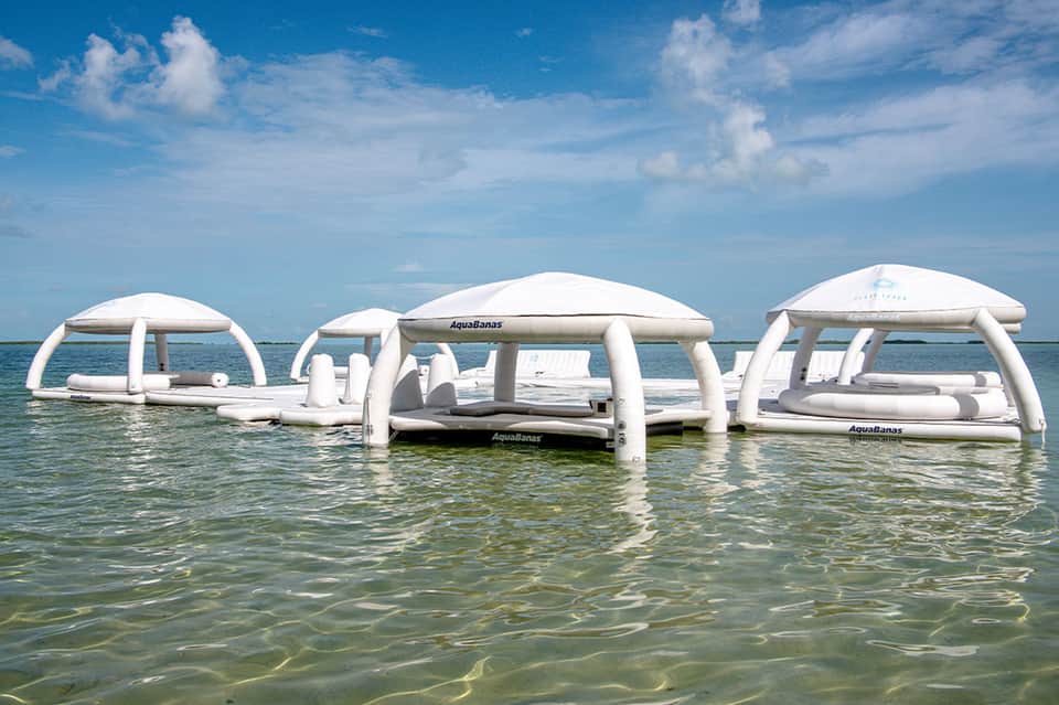 Floating white inflatable cabanas with shade covers in shallow turquoise ocean water