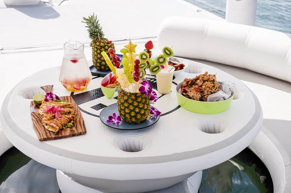 Yacht deck spread with tropical fruits, cocktails, and gourmet appetizers