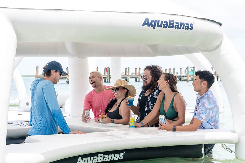 Group of guests at white bar on AquaBanas boat with water and docks visible in background