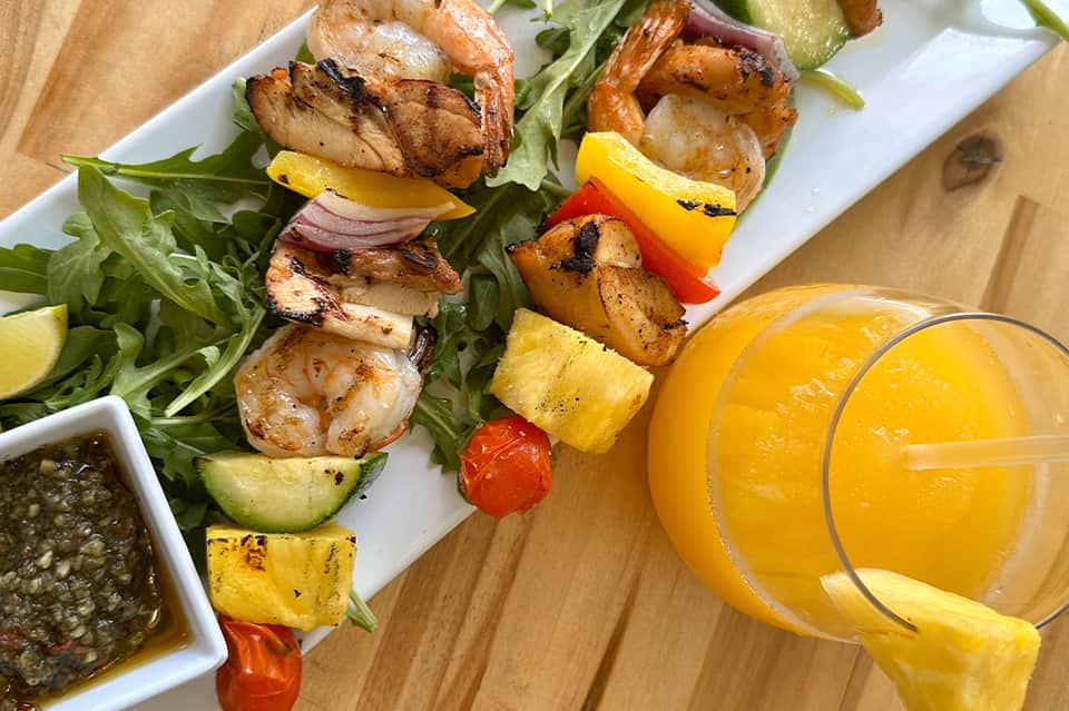Grilled shrimp and vegetable skewers on arugula with fresh orange juice and lime
