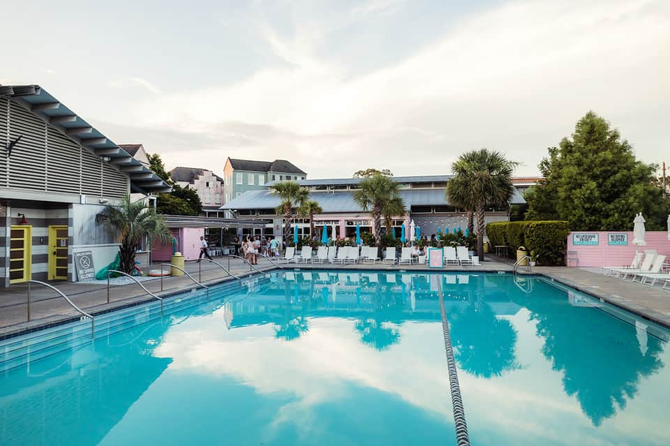 Olympic-sized lap pool reflecting clouds with resort buildings, palm trees, and lane dividers