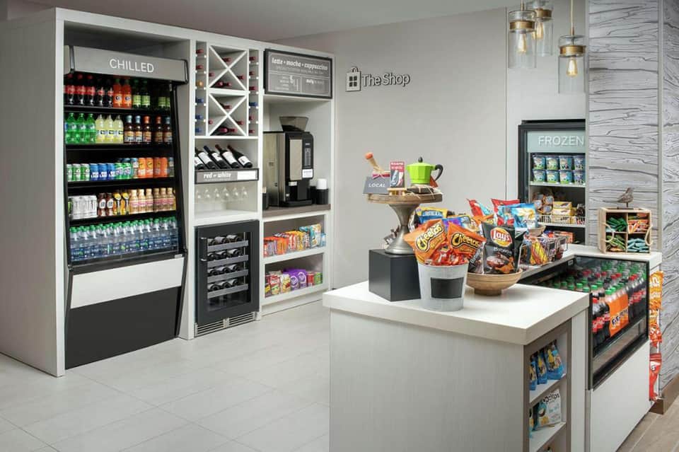 Hotel convenience shop with refrigerated beverage display, snacks, and frozen section